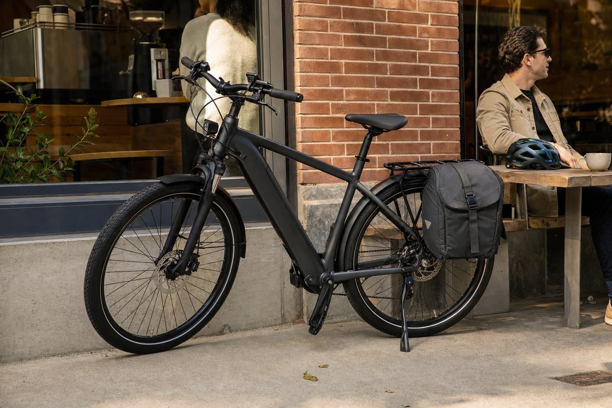 Electric commuter bike with panniers parked outside a coffee shop in an urban setting